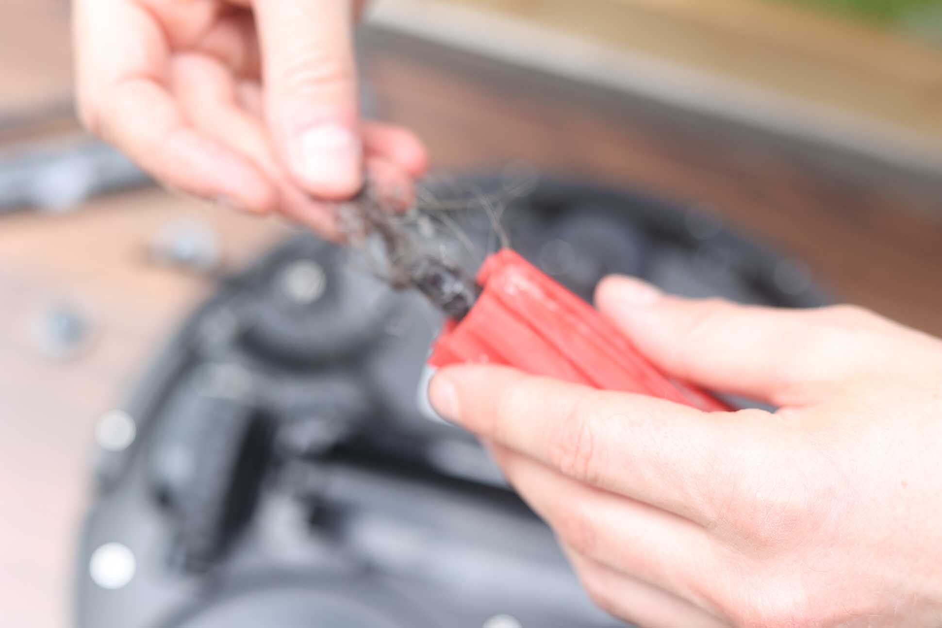 Haare werden aus der Hauptbürste mit Hilfe einer Schere entfernt.